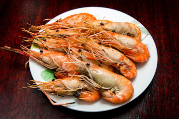 Grilled river shrimps on white plate on wooden background, Thai style food
