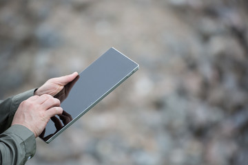 Businessman using a smart tablet on a green summer day. Man in green shirt using tablet outdoors.