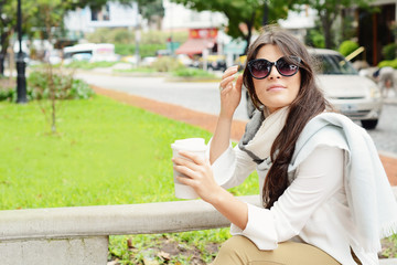 Woman holding paper coffee cup in the street.