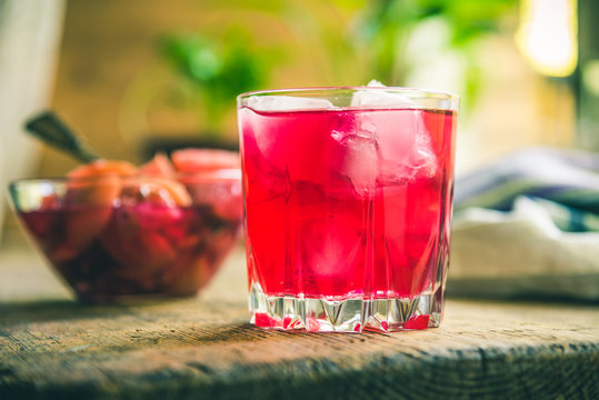 Red fruit drink with ice on a rustic background