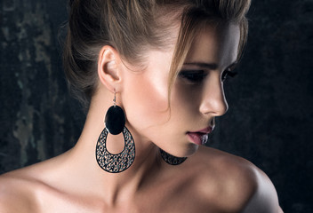 Large earrings. Closeup portrait in the shadows of a young woman in profile