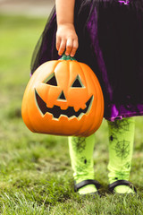 Little girl holds an orange jack o lantern Halloween decoration