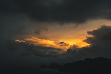 dark dramatic sky during golden yellow sunset on exotic island, thailand