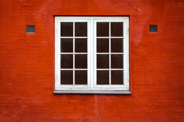 Beautiful old window on a background of the red brick wall. Architecture.