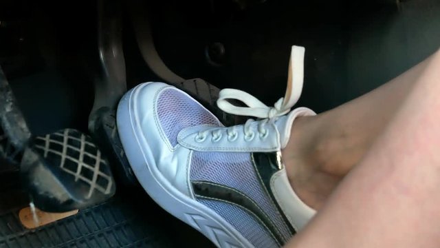 Girl on white snickers shoes pressing car pedals 4k