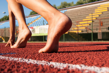 Bare feet ready to depart on a red lane of the athletic ring