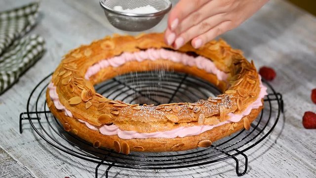 Sifting powdered sugar over a paris brest.