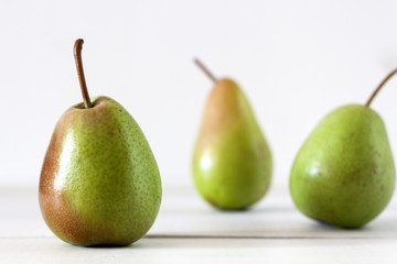Fresh ripe pears lie on a white wooden table