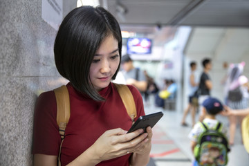 Beautiful young woman traveler using smartphone at a train station , Transportation and travel lifestyle concept