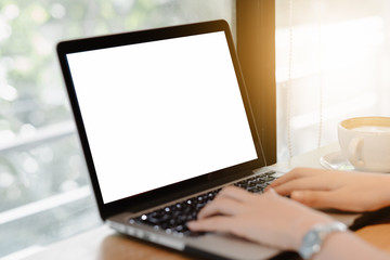 Mockup image of a businesswoman using laptop with blank white desktop screen with coffee cup on wooden table in cafe