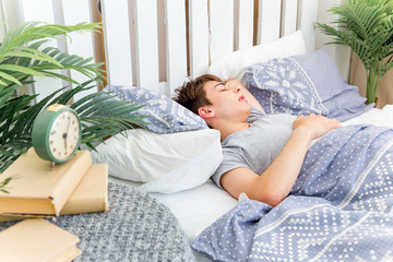 Handsome young man sleeping in white bedding