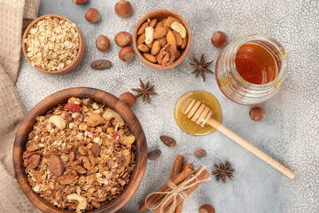 Homemade granola in wooden bowl with ingredients - oat, nuts, honey and spice cinnamon and anise