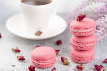 Pink macaroons with dried flower buds and cup of coffee. Pastel colored.