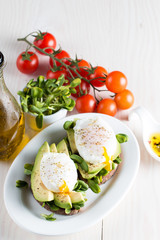 Avocado toast, cherry tomato on wooden background. Breakfast with toast avocado, vegetarian food, healthy diet concept. Healthy sandwich with avocado and poached eggs.