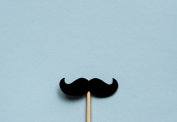 Black mustache on light blue background for Movember concept which is an annual event involving the growing of moustaches during the month of November to raise awareness of men's health issues.