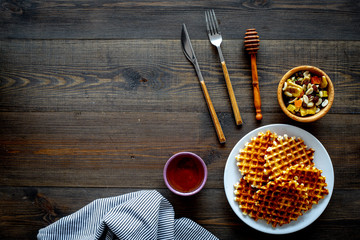 Traditional belgian waffles with dried fruit, nuts and caramel on dark wooden background flat lay copy space