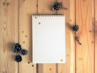 Mock up notepad. Open notebook empty blank page on wooden background with fir cones and confetti stars. Top view