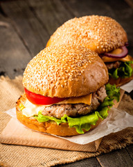 Close-up photo of home made hamburger with beer made of beef, onion, tomato, lettuce, cheese and spices. Fresh burger closeup on wooden rustic table with potato fries and chips.