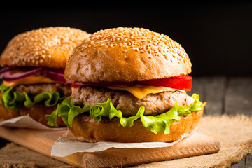 Close-up photo of home made hamburger with beer made of beef, onion, tomato, lettuce, cheese and spices. Fresh burger closeup on wooden rustic table with potato fries and chips.