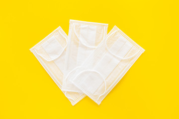 Flu prevention. Medical face masks on yellow background top view copy space