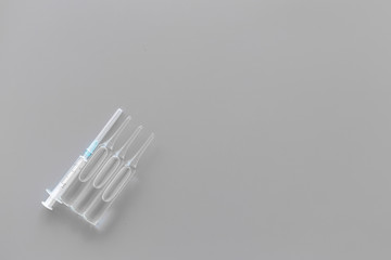 Flu vaccination concept. Syringe and ampoulie on grey background top view space for text