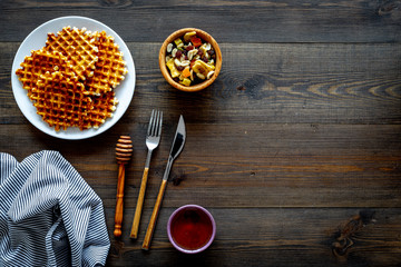 Traditional belgian waffles with dried fruit, nuts and caramel on dark wooden background flat lay copy space