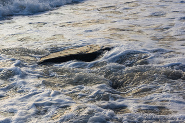 pebble stones on the sea beach, the rolling waves of the sea with foam