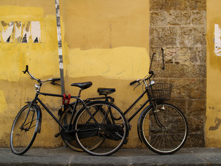 Fototapeta na wymiar black bicycles are parked on narrow street in florence, italy