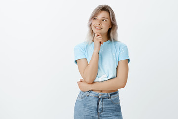What if. Portrait of dreamy attractive woman in good mood, holding hand on chin and smiling broadly...