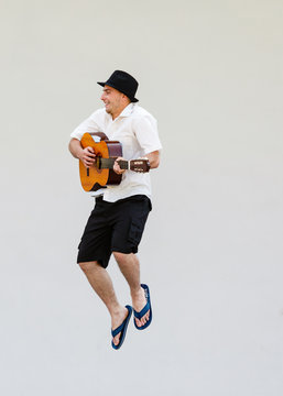 Man in sun hat jumping with guitar