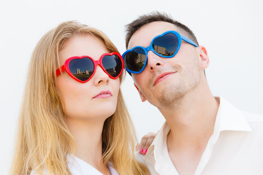 Man and woman wearing heart shape sunglasses
