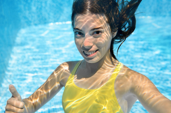 Girl swims in swimming pool underwater, happy active teenager dives and has fun under water, kid fitness and sport on family vacation on resort
