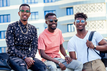 a group of three fashionable cool African American guys students communicating on the street