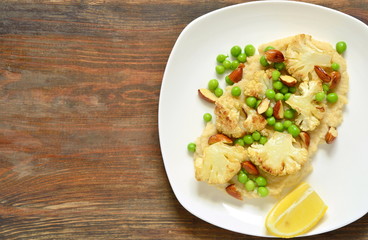 Salad with roasted cauliflower and green peas, almonds served on vegetable puree, top view, copy space