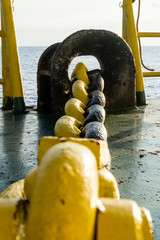 Yellow painted anchor windlass chain on a construction barge at oilfield