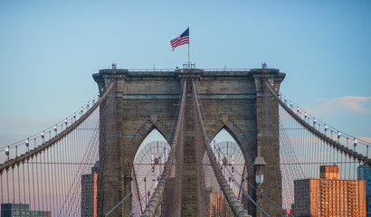 Close up view of one of the towers structures of the brooklyn bridge, flying the Stars and Stripes on the top
