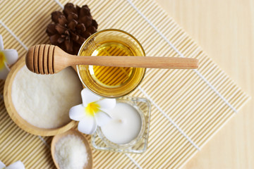 Homemade spa set which consists of body and facial scrub, hair treatment oil, aroma candle and flowers in oriental style on white background, body and hair care concept