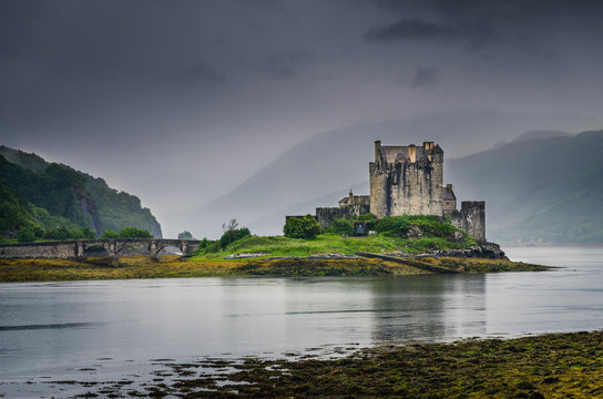Scottish medieval Eilean Donan castle peaking from a lake during cloudy weather