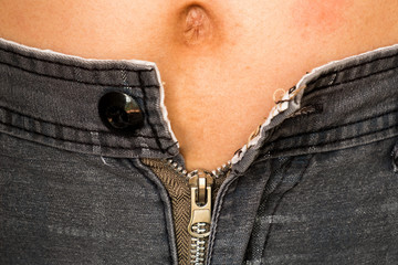 A overweight man can't tight his pants because his fats in belly. He needs a gym to firming his shape.