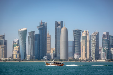 The skyline of Doha with a traditional boat in the foreground in Qatar, on a blue sky day, winter time, seen from the MIA Park © LMspencer