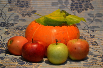 тыква под осенним листом и яблоками