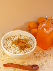 Healthy breakfast. White plate of oatmeal with dried apricots, a glass of an apricot juice and fresh apricots on a white table.