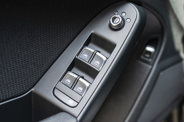 Door handle with Power window control buttons of a luxury passenger car. Black leather interior of the luxury modern car. Modern car interior details. Car detailing