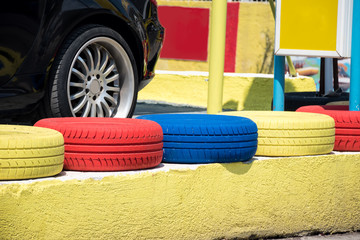 Colorful painted car tires standing in a row in front of a car wheel. Car rent concept.