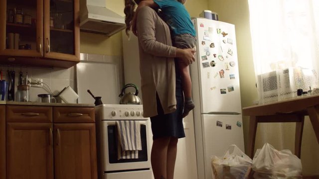 Mom hugs son in the kitchen. Concept of care and love. Excellent relationship with mother and son