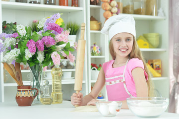 Cute girl in chefs hat making dough