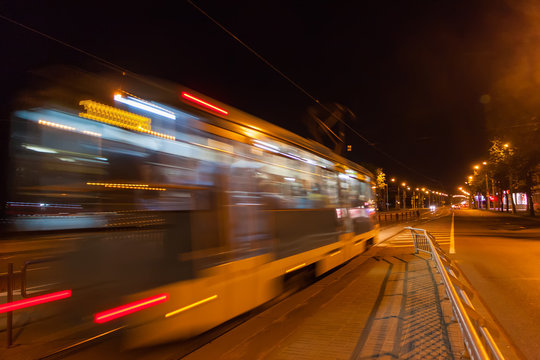 The motion of a blurred tram down the street in the evening.