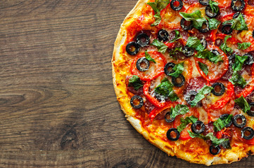 Pizza with Mozzarella cheese, salami, pepper, pepperoni, Tomatoes, olives, Spices and Fresh Basil. Italian pizza on wooden background. with copy space. top view