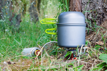 Gas burner with a bowler hat on the green grass, cooking in the hike