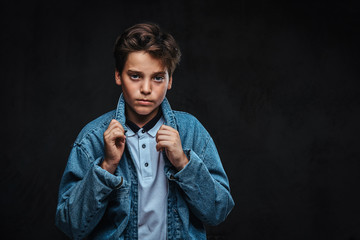 Fashionable young guy dressed in a t-shirt and denim jacket posing in a studio.